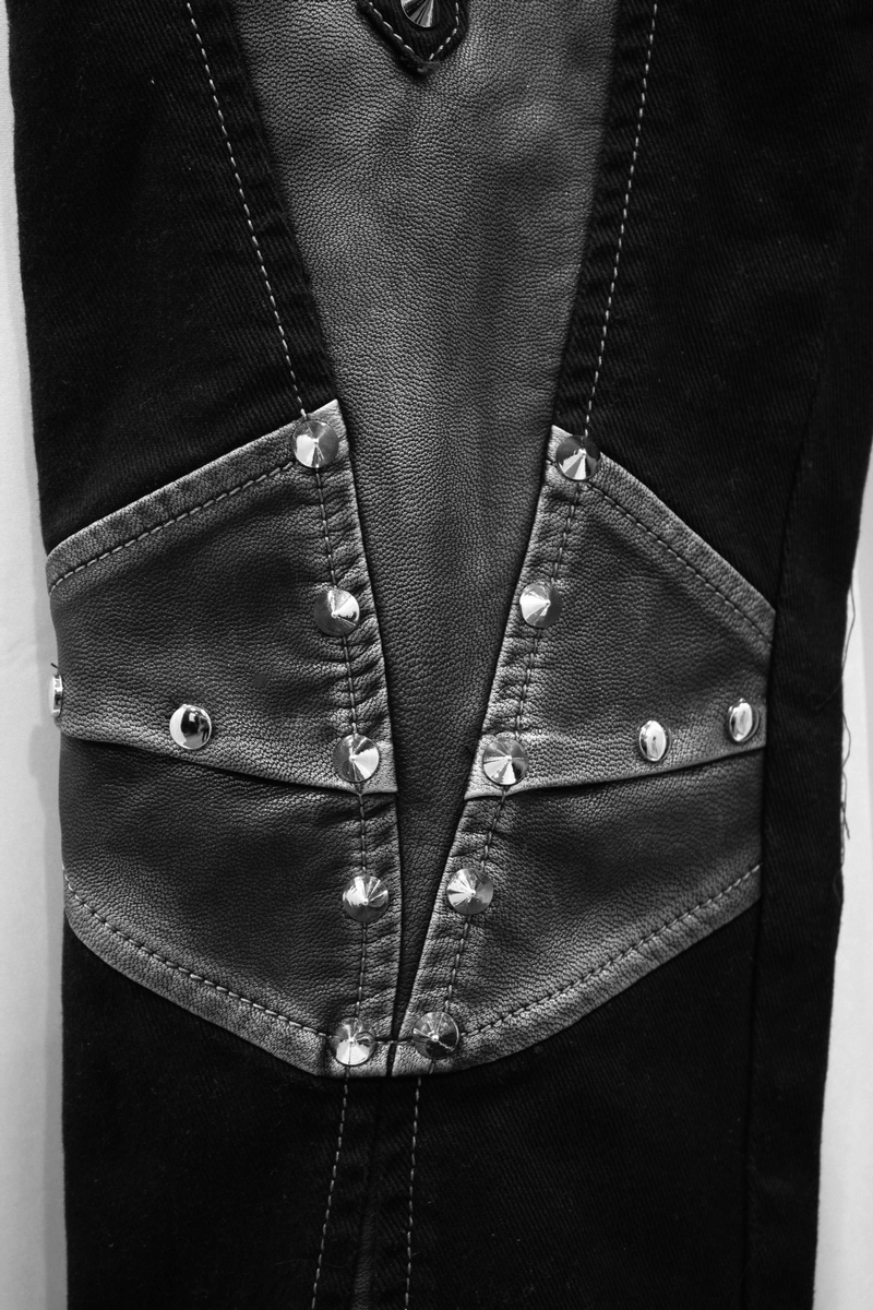 Close-up of gothic studded black pants with leather accents and metallic details for punk-style fashion.