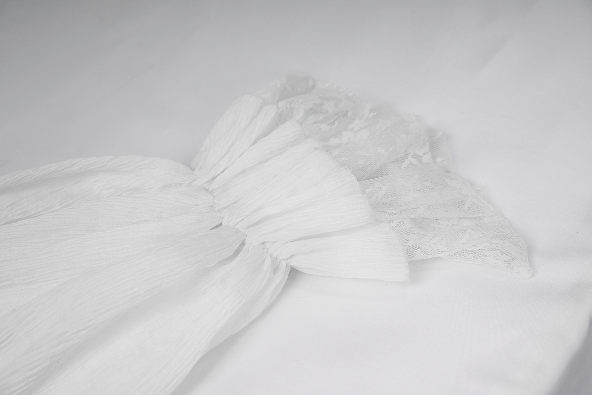 Elegant white long sleeve gothic shirt with lace cuffs and vintage ruffles on a soft background.