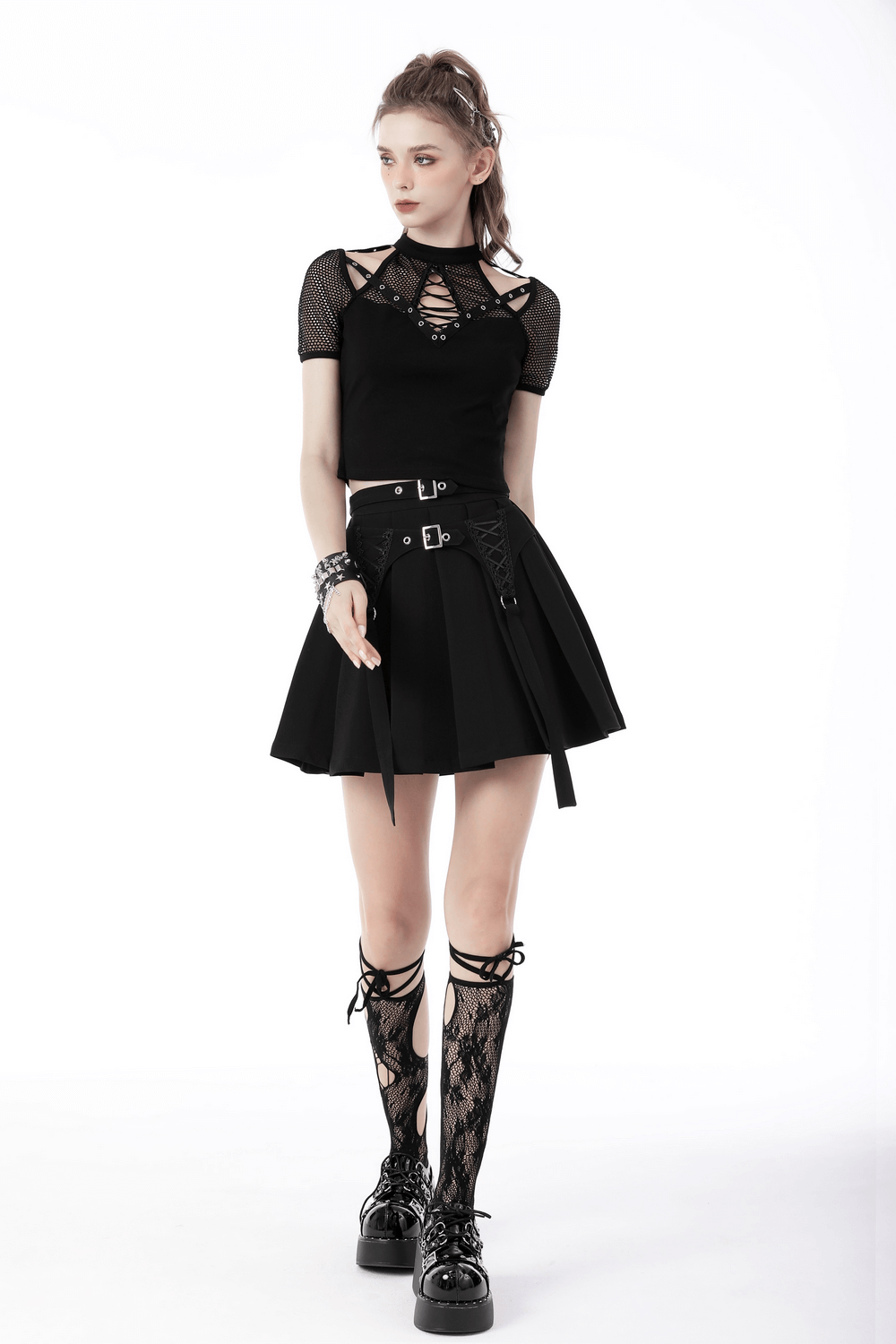 Gothic black pleated mini skirt with lace-up details and buckle accents, styled with a chic black top and lace-up boots.