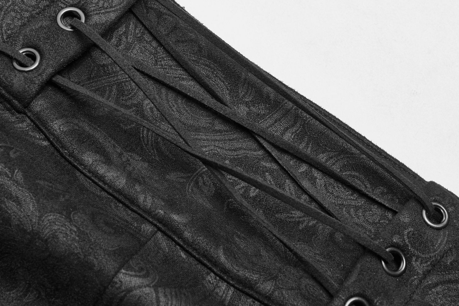 Close-up of gothic long overskirt detailing with black lace-up closure and intricate floral pattern.