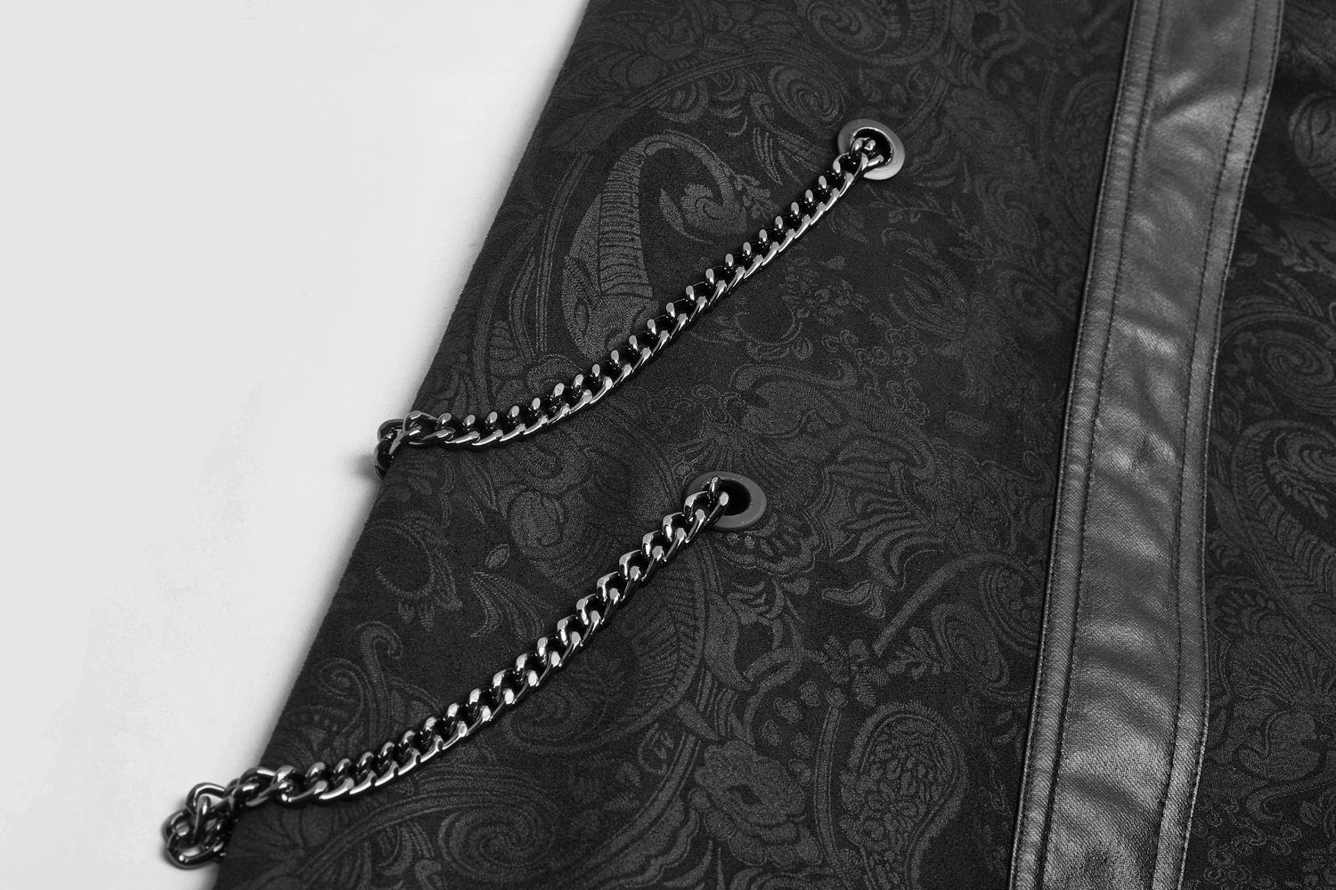 Close-up of gothic suede long overskirt featuring decorative chains and intricate floral detailing.
