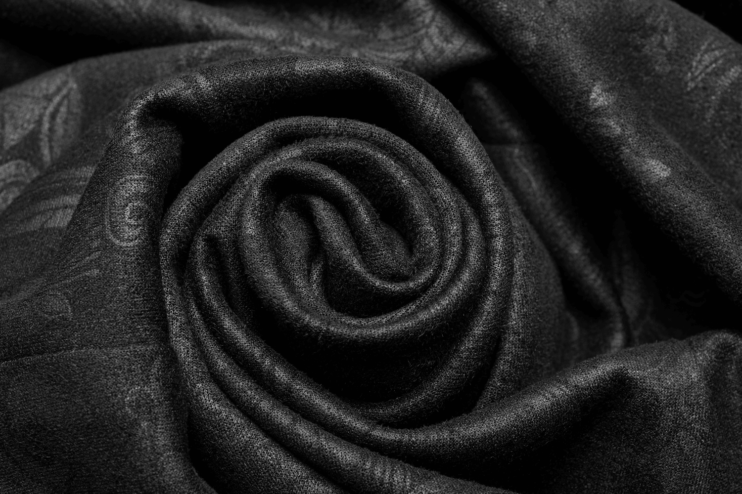 Close-up of luxurious black suede fabric, elegantly rolled, perfect for gothic fashion creations.