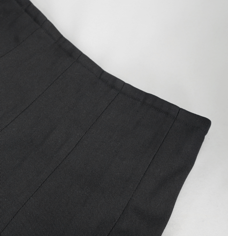 Close-up of the waistband of a black kilt, showcasing sleek lines and a tailored finish.
