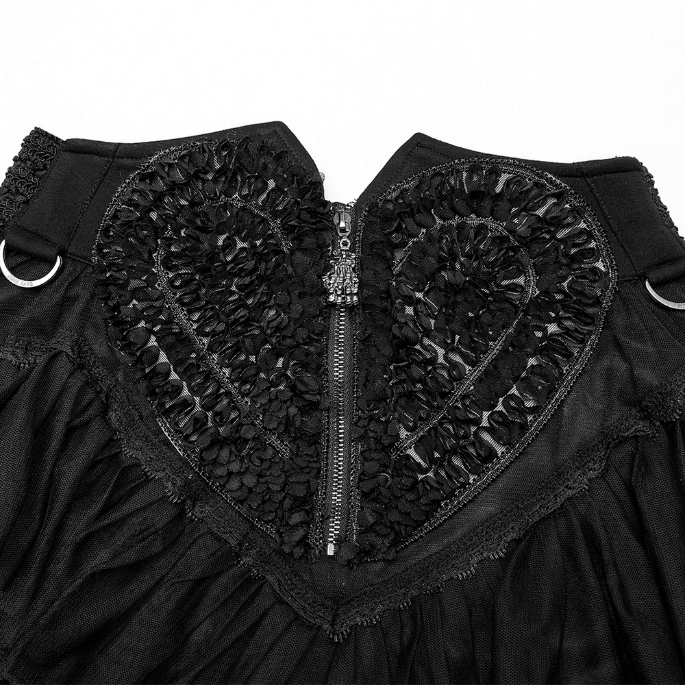 Close-up of gothic black layered skirt with heart-shaped floral design and skeleton hand zipper.