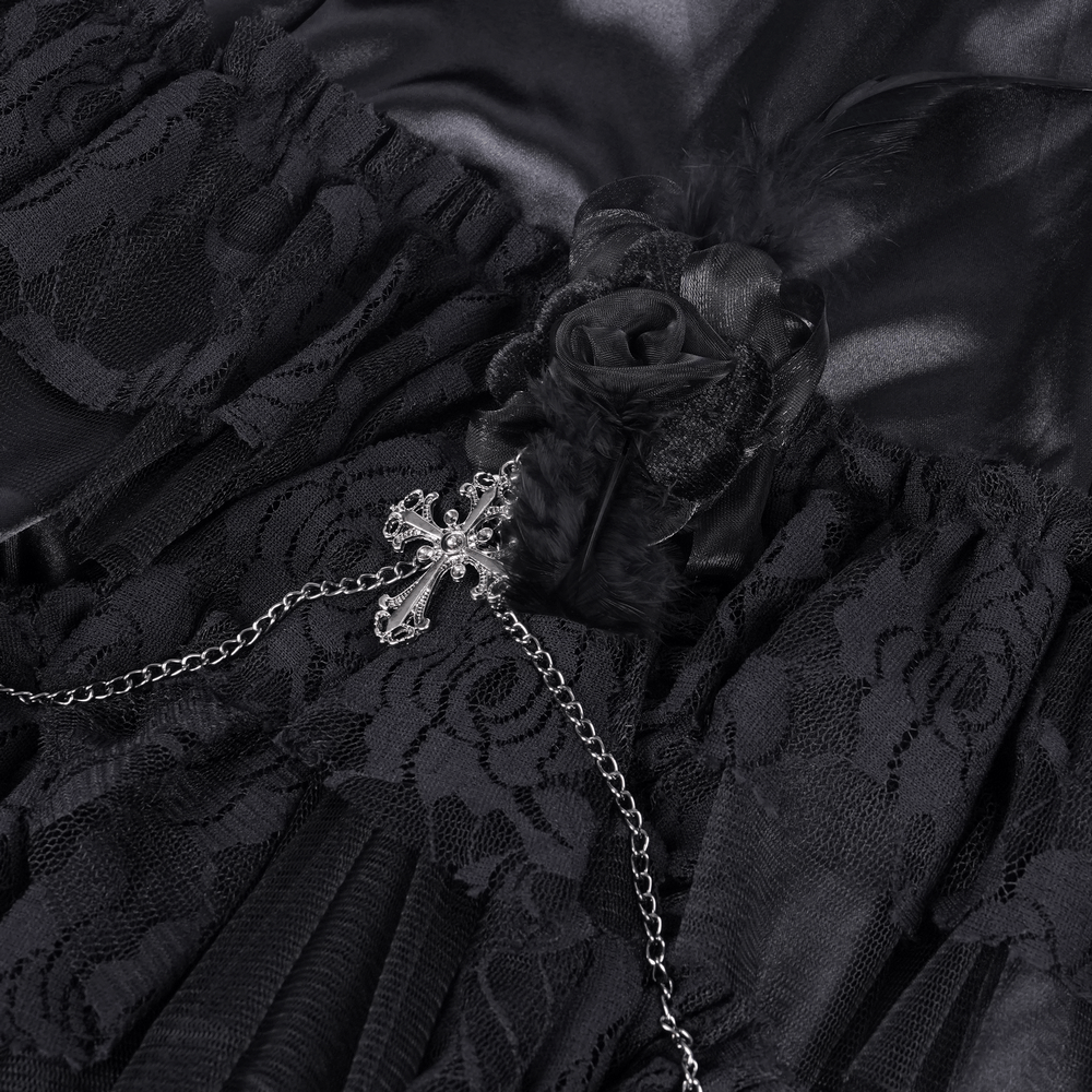 Close-up of a gothic tulle skirt featuring black lace, floral accents, and a silver chain with a cross detail.