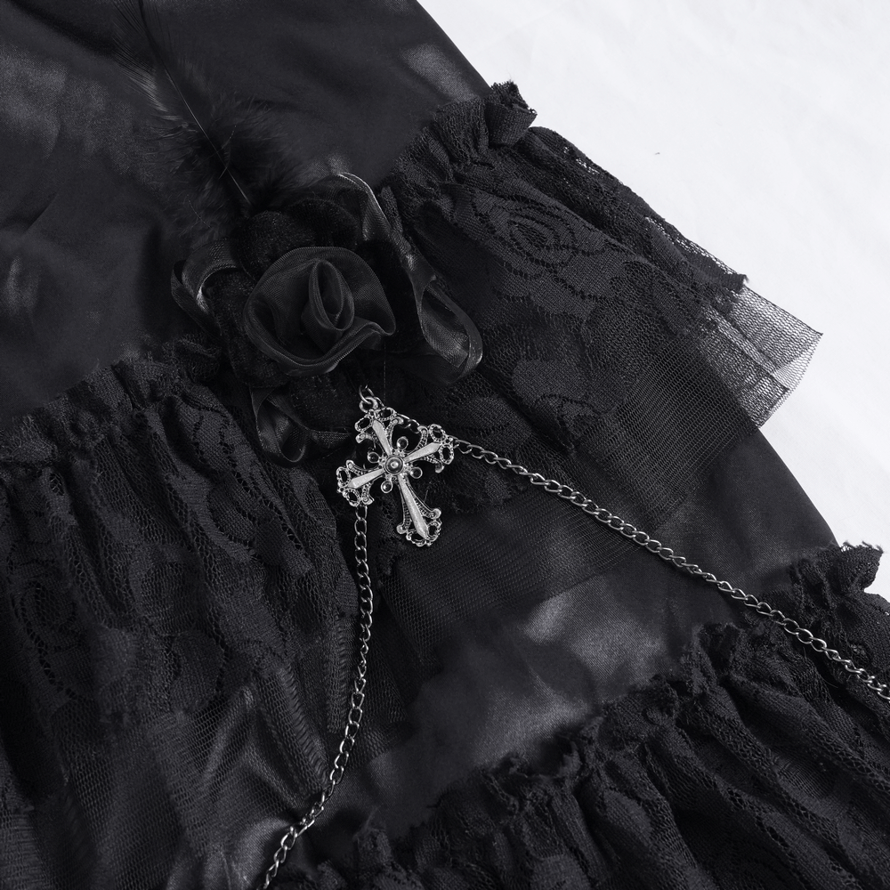 Close-up of a layered black lace skirt featuring a floral accent and a decorative chain with a gothic cross.