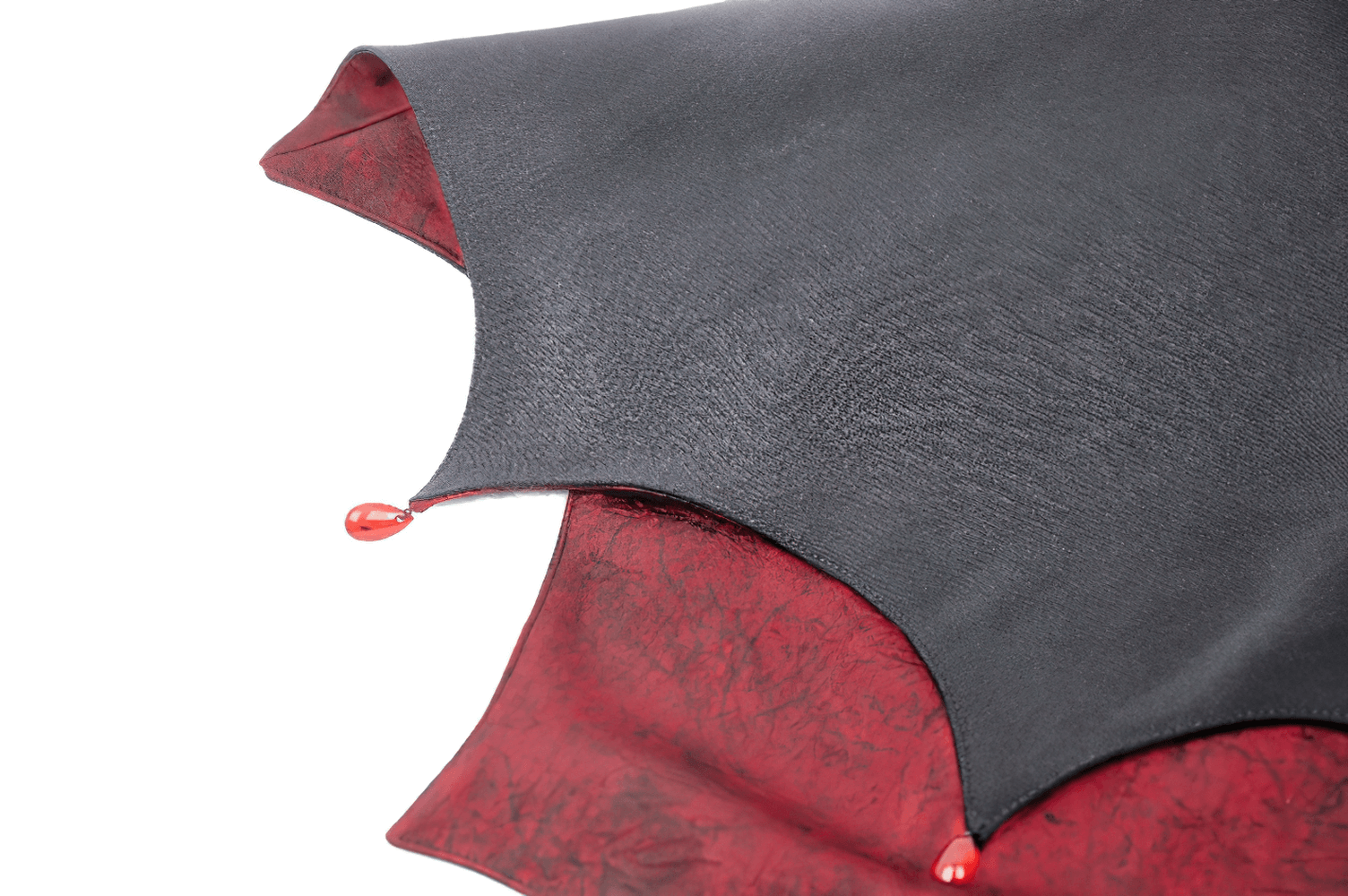 Close-up of Gothic vampire cape featuring black fabric, blood-red lining, and jewel clasp detail.