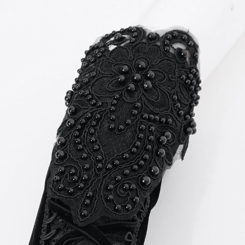Close-up of gothic black lace detailed gloves featuring intricate floral patterns and beads, perfect for elegant evenings.
