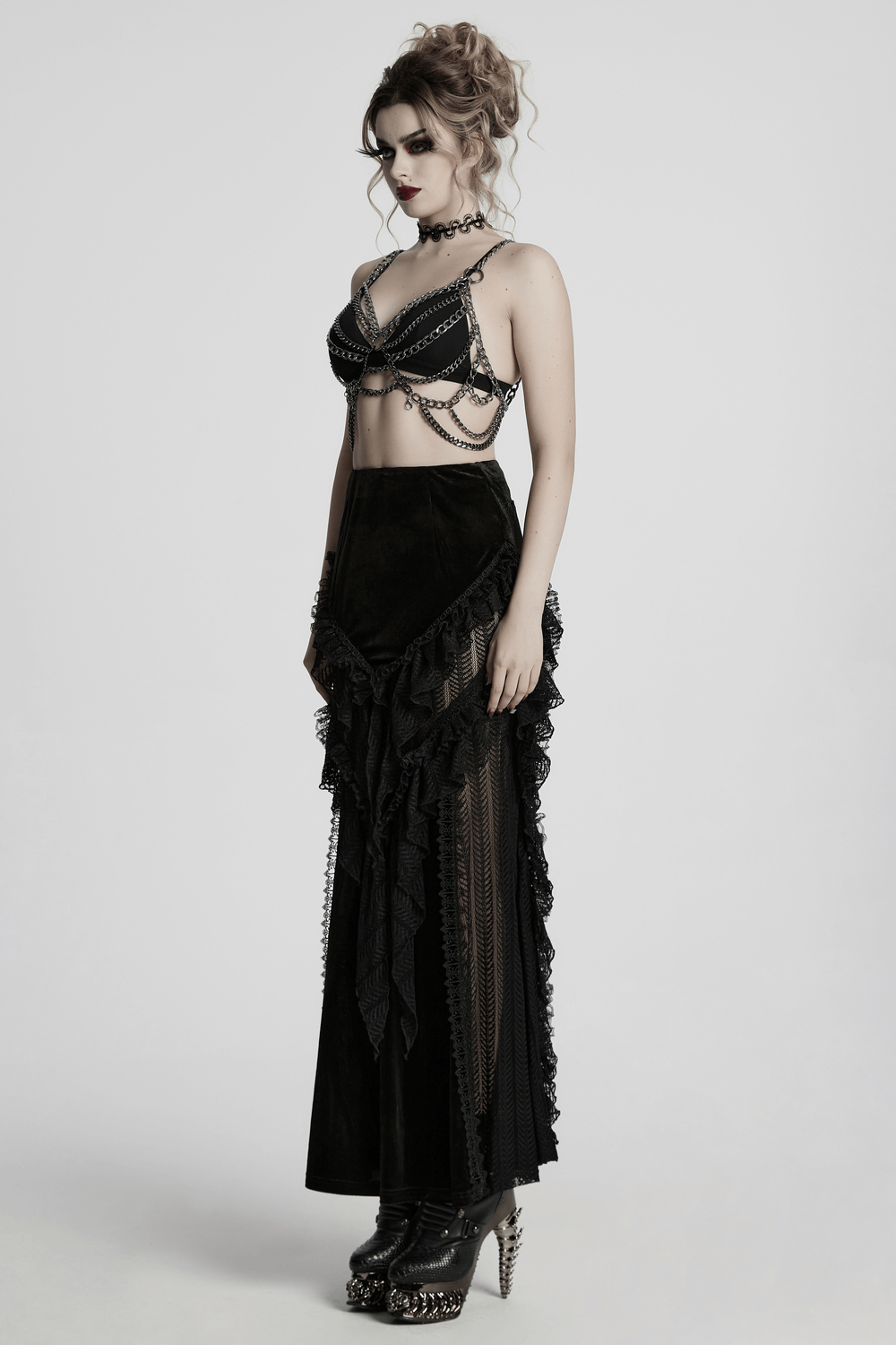 Gothic velvet and lace ruffle skirt with mesh detailing, worn with a chained bralette and edgy heels.