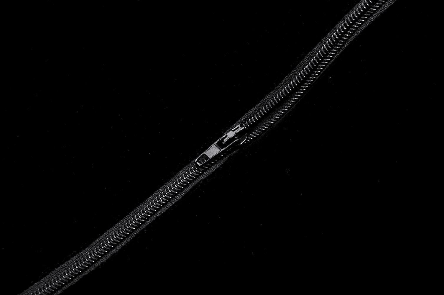 Black zipper detail on a black background, showcasing its smooth glide and sturdy design.