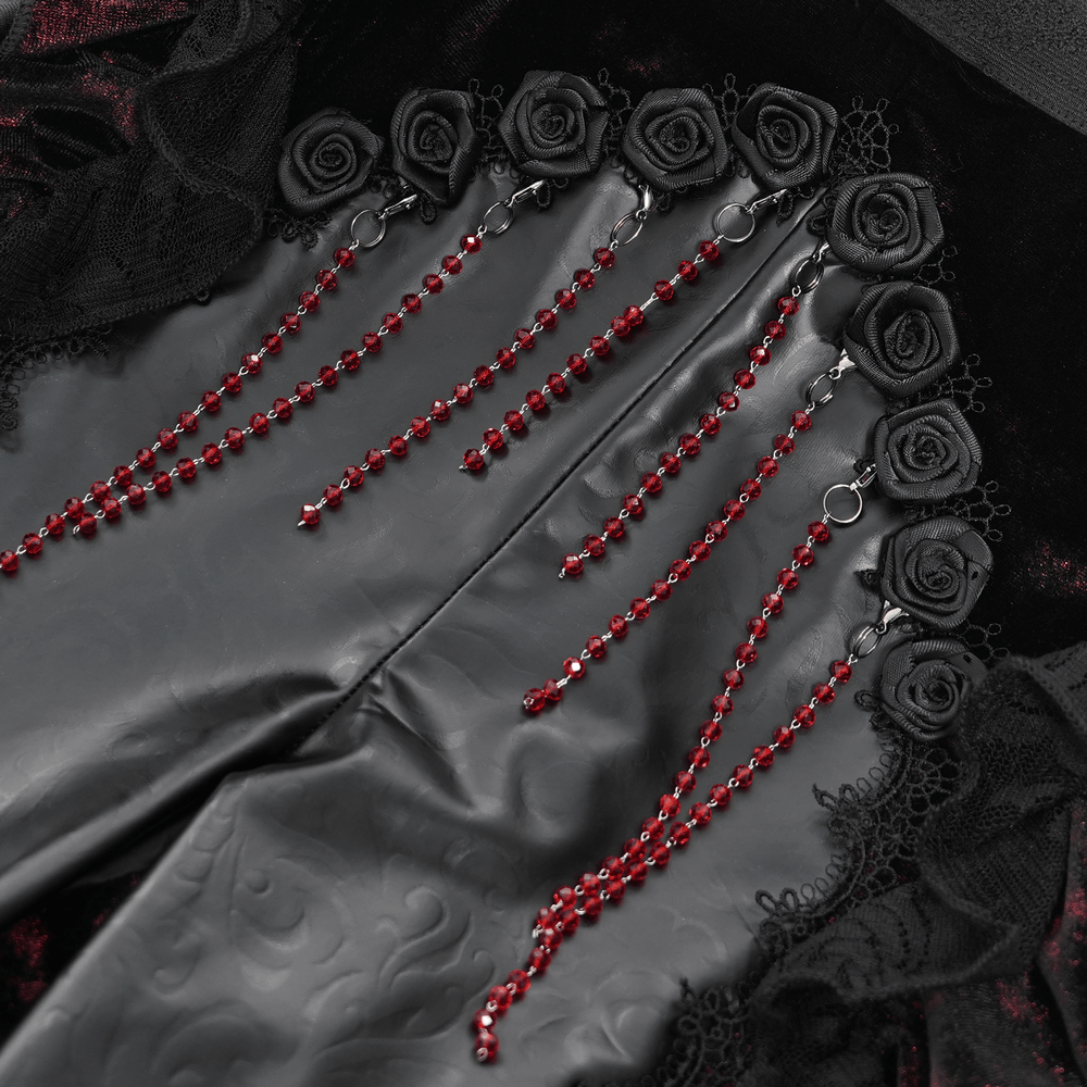Close-up of gothic velvet flare pants showcasing rose appliqués and cascading red bead accents.