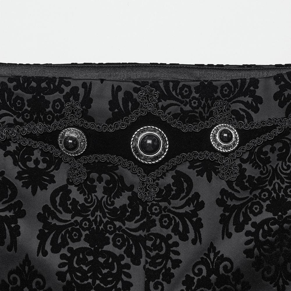 Close-up of black velvet suit pants featuring ornate gemstone buckles and intricate floral flocking design.