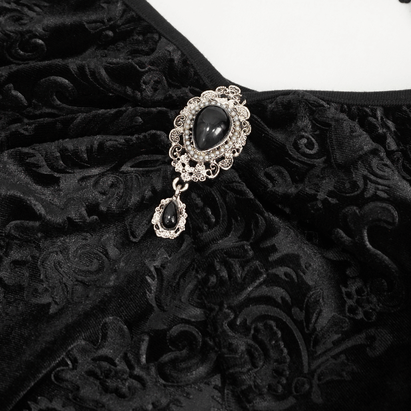Close-up of a gothic velvet top featuring intricate black embellishments and an elegant silver brooch.