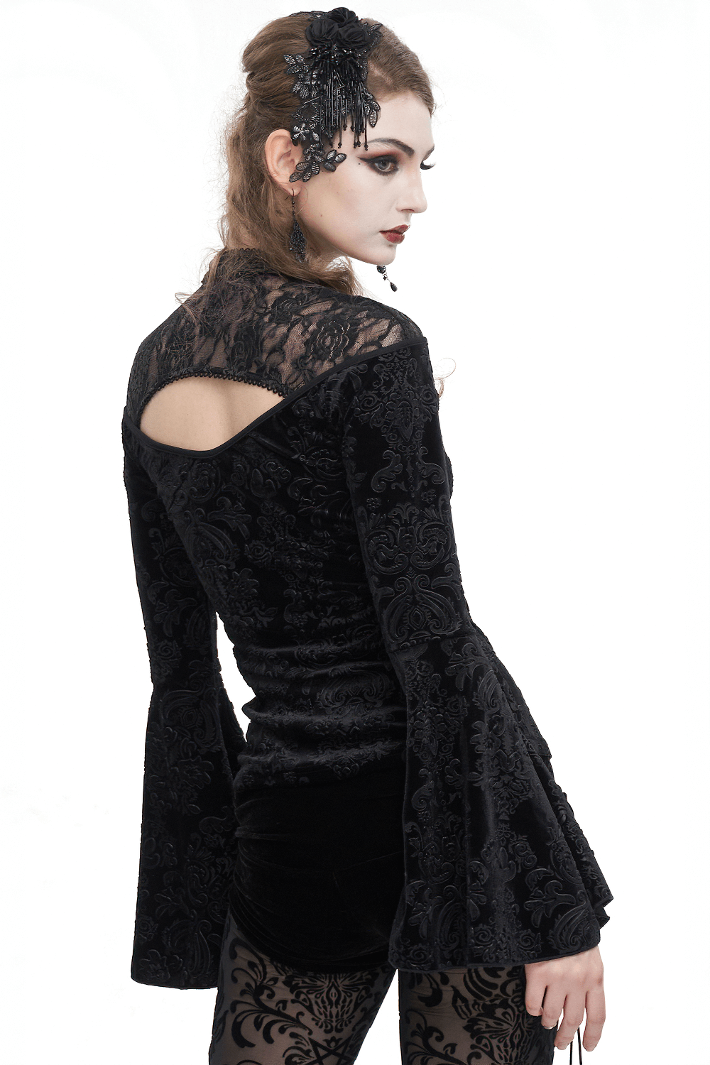 Back view of a woman in a gothic velvet V-neck top with long bell sleeves and lace detailing.