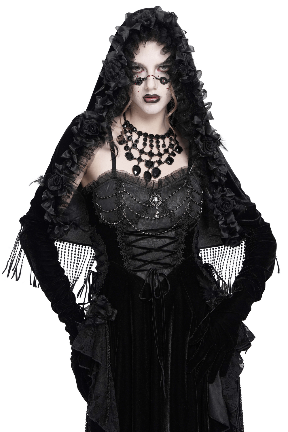 Model wearing a gothic velvet hooded cape with floral detailing and fringe, exuding vintage elegance.