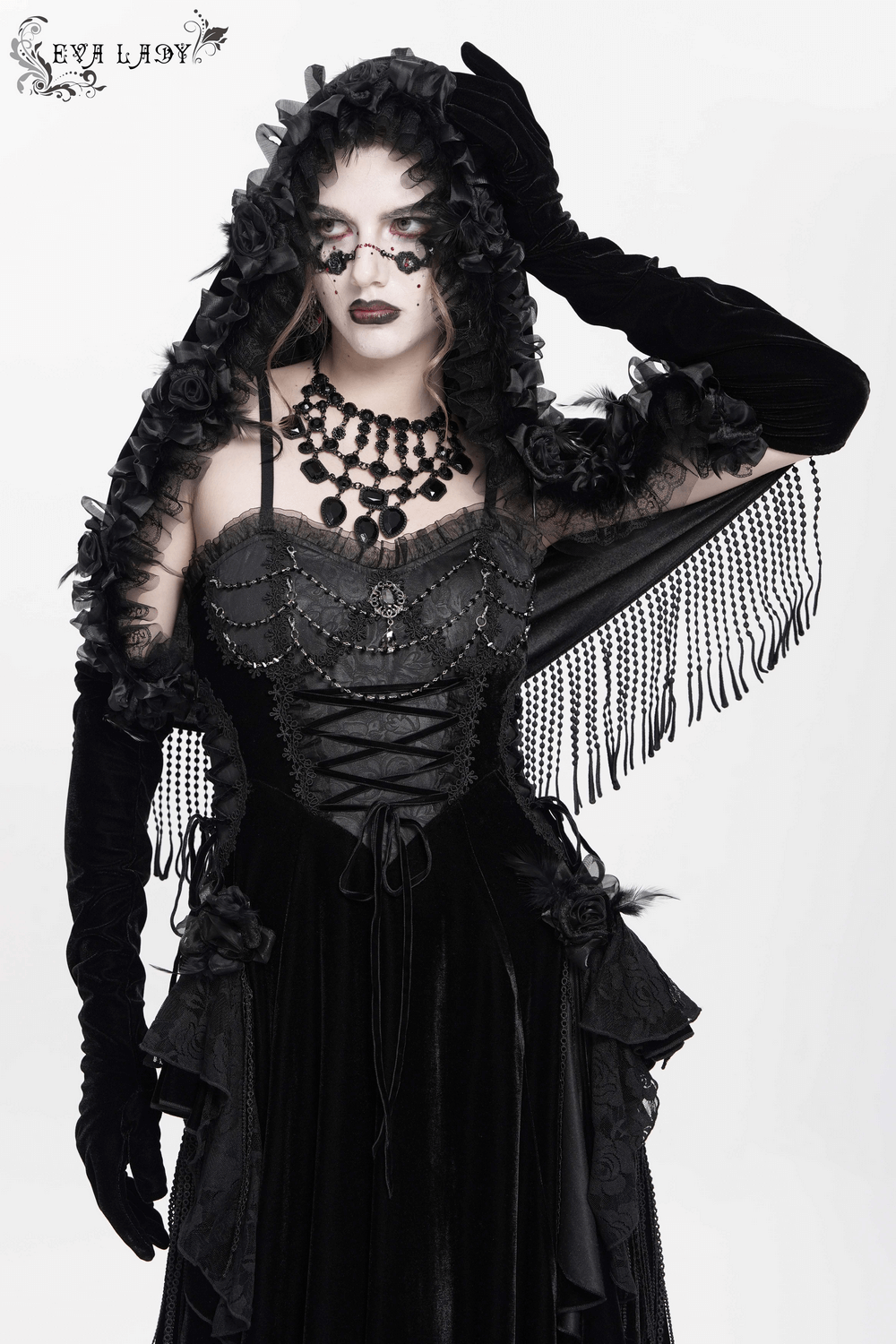 Gothic velvet hooded cape with floral detailing and fringe, styled elegantly for a dramatic look.