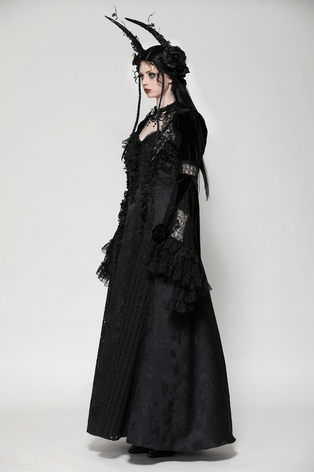 Gothic woman in a dramatic black lace and velvet outfit with flared sleeves and a lace-trimmed collar.