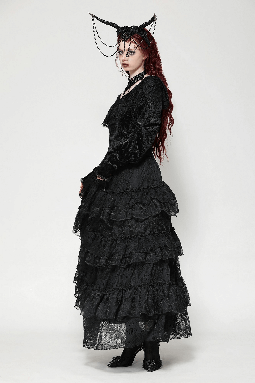 Elegant woman in a gothic layered black lace dress with dramatic accessories and striking makeup.