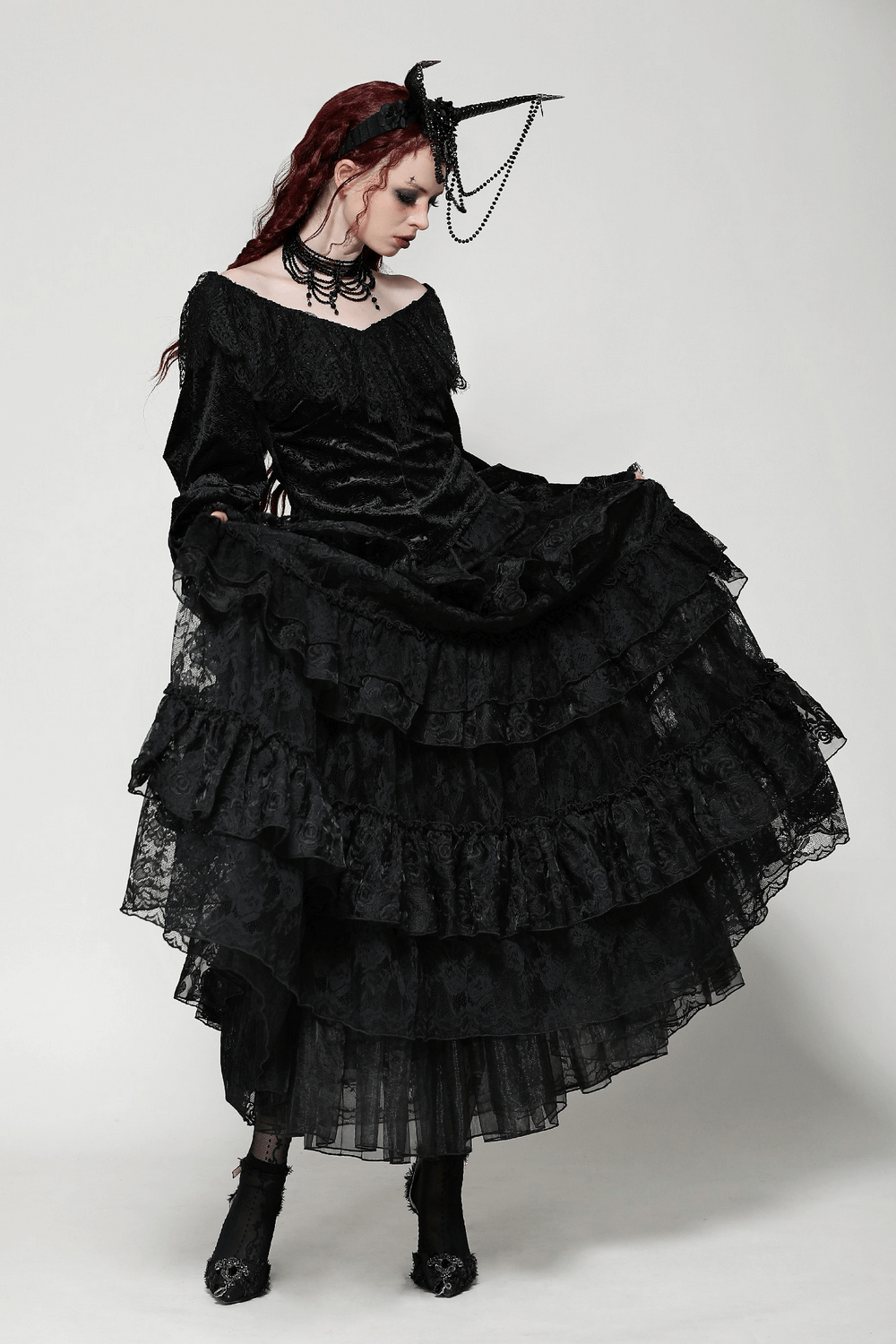 Elegant woman in a black velvet lace off-shoulder gown with ruffles, showcasing gothic fashion and dark romance.