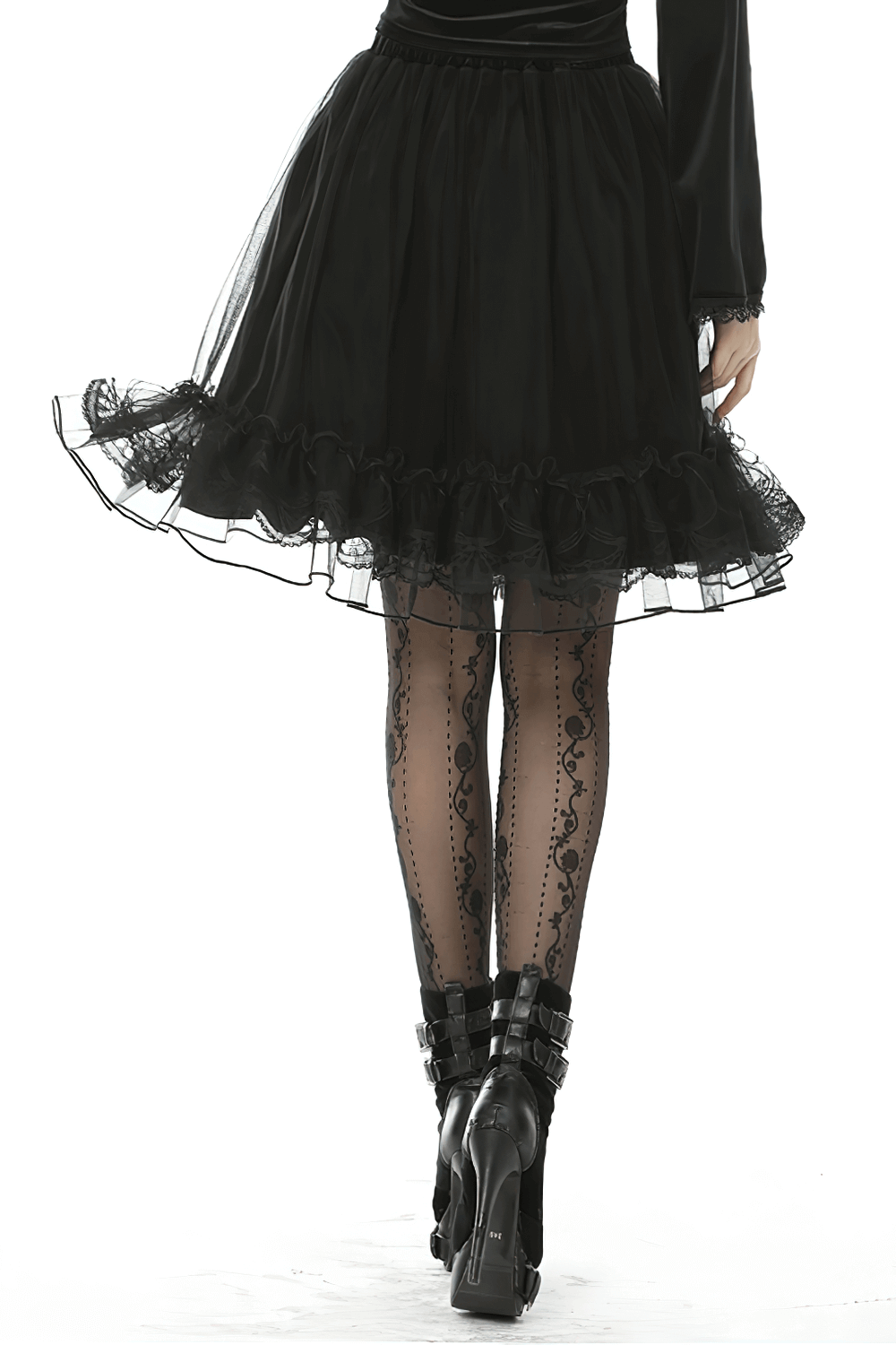 Model showcasing a black velvet skirt with lace trim and mesh overlay, paired with stylish black stockings and heels.