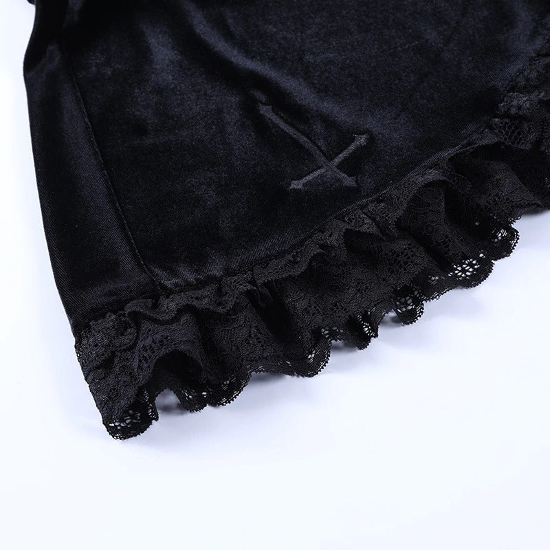 Close-up of a Gothic velvet pleated mini skirt showing black lace ruffles and cross embroidery details.