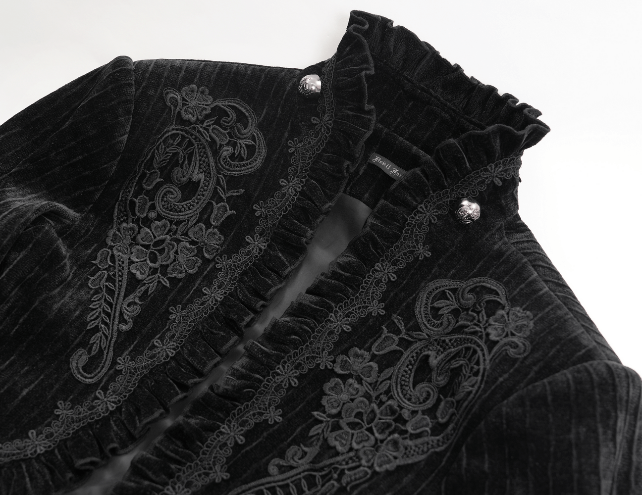 Black velvet swallowtail jacket with intricate embroidery and ruffled collar, showcasing gothic elegance and detail.