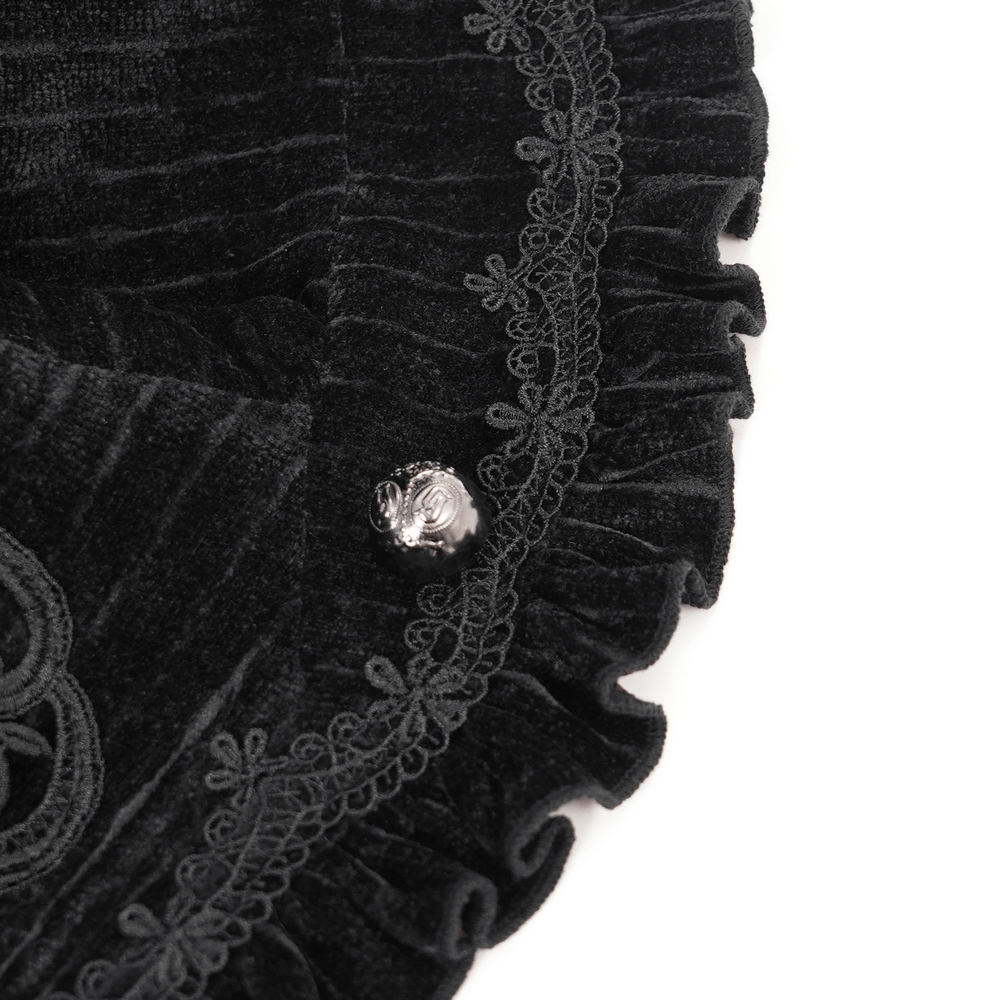 Close-up of black velvet fabric with intricate lace detailing and a silver button on a gothic swallowtail jacket.