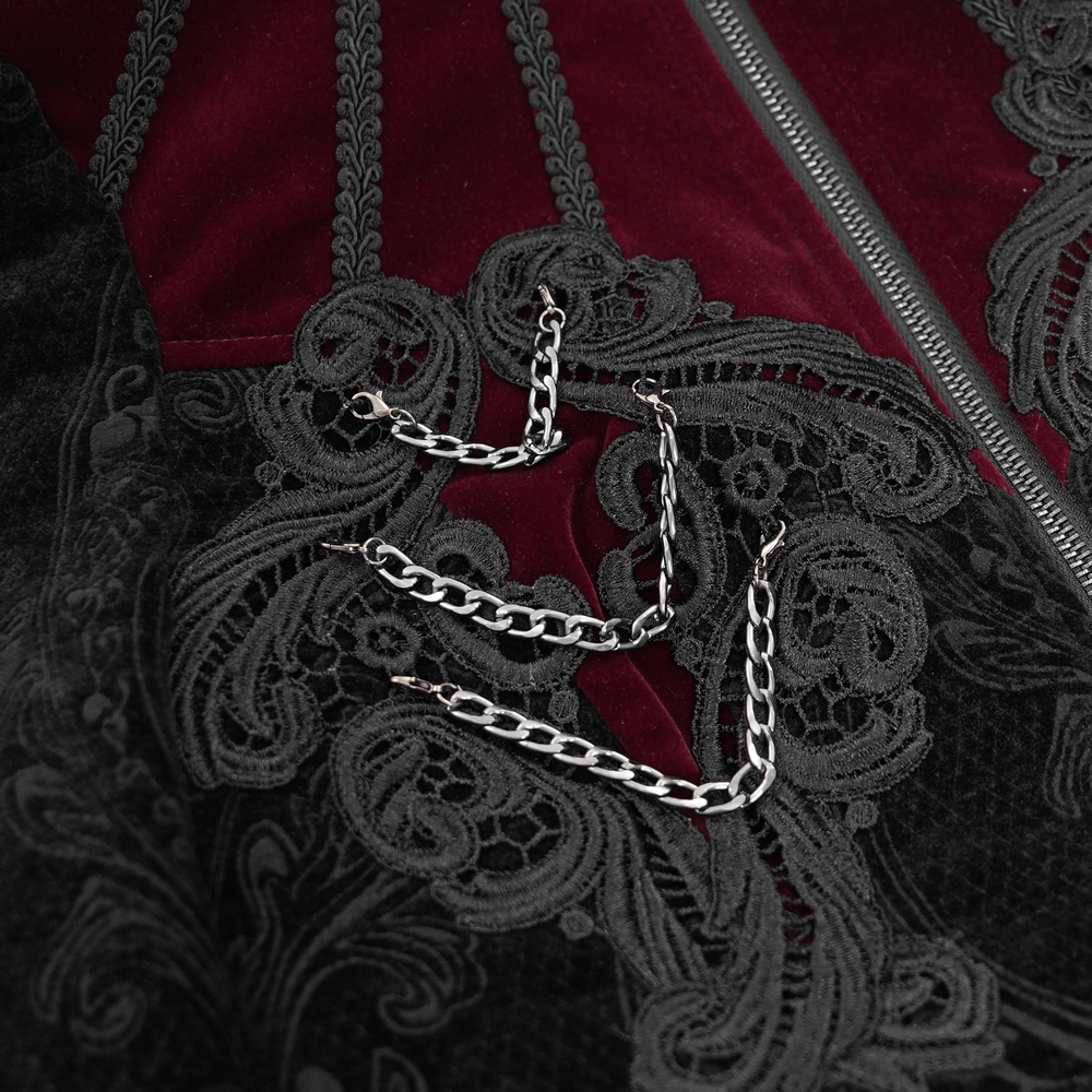 Close-up of gothic Victorian jacket with intricate embroidery and silver chain embellishments on a rich velvet background.