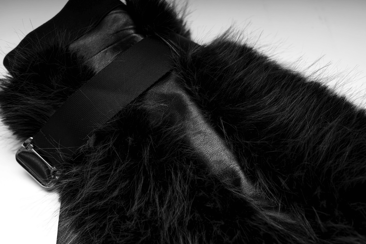 Close-up of black faux fur leg warmers featuring an adjustable strap and detachable loops for a customizable fit.