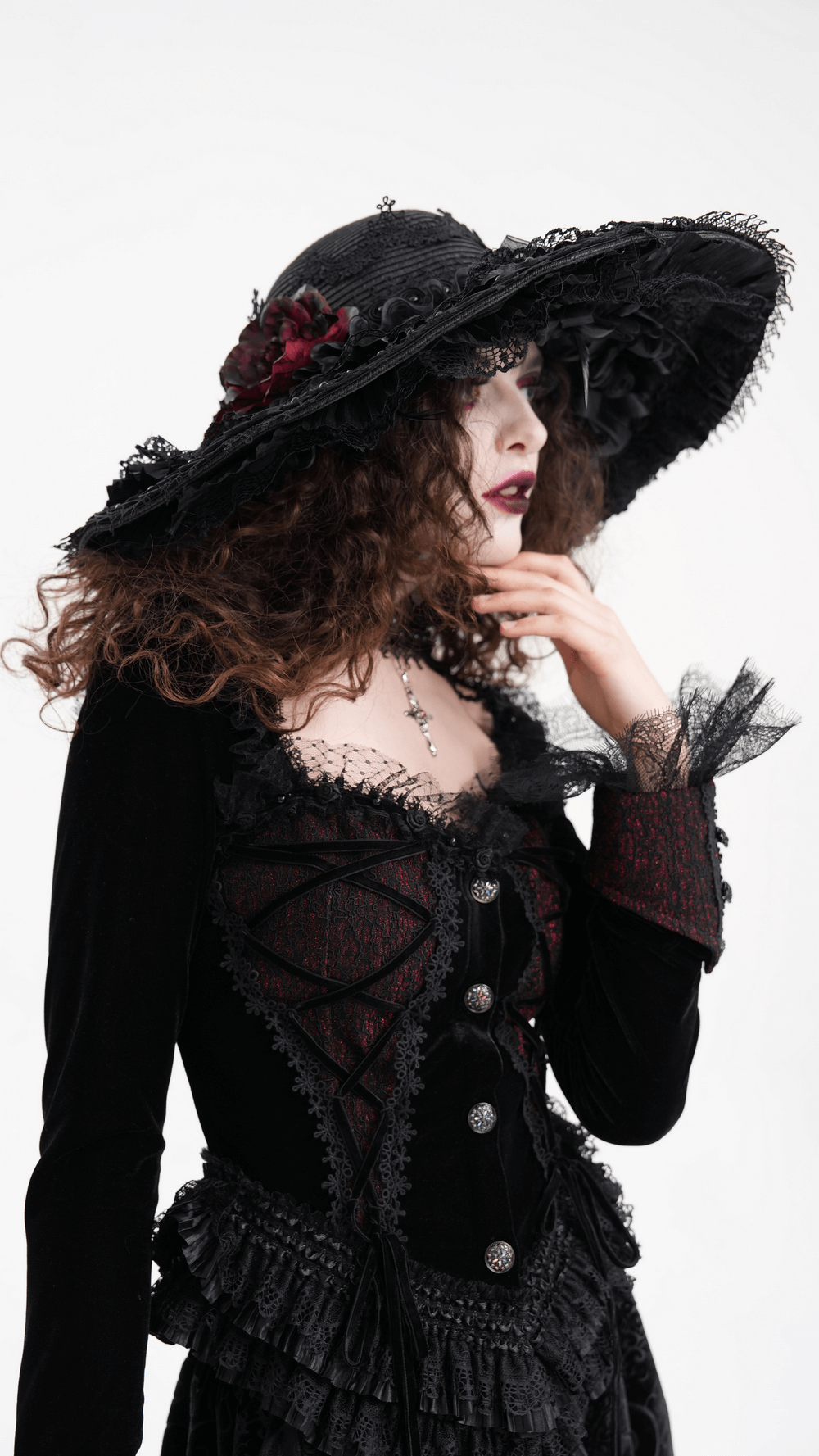 Gothic wide-brim hat with black lace and red floral accents, worn elegantly by a model in Victorian-inspired attire.