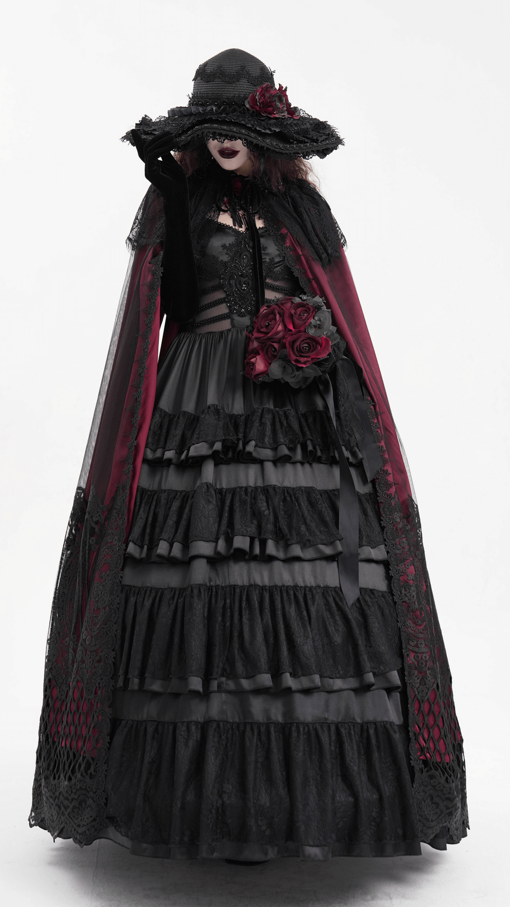 Victorian gothic woman wearing wide-brim hat with lace and red floral accents, in elegant dark attire.