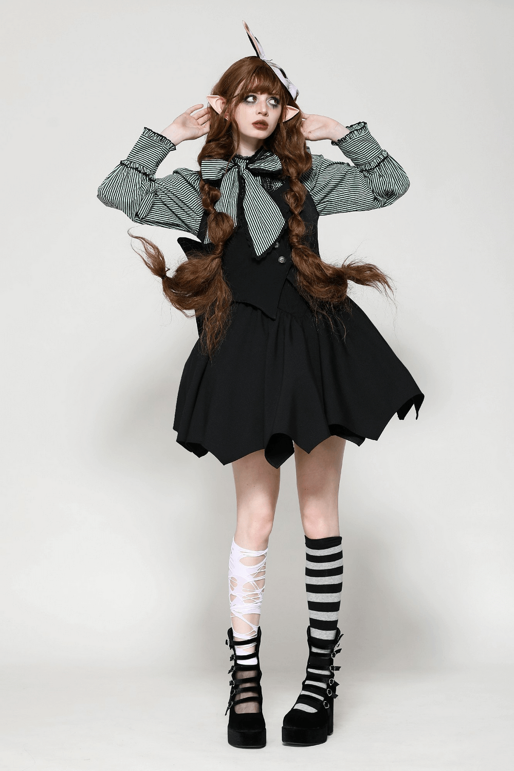 Dark whimsical fashion model in layered black and checkered outfit with striped socks and chunky platform shoes.