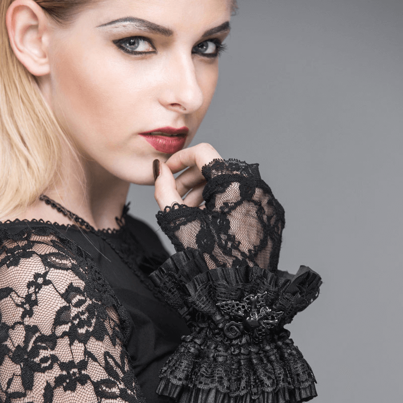 Gothic woman showcasing elegant black fingerless lace gloves with floral embroidery and a striking skull pendant.
