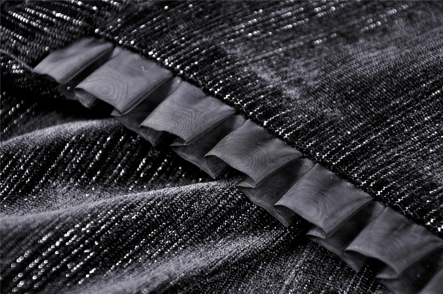 Close-up of black fabric with intricate texture and ruffled detailing, showcasing gothic dress elegance.