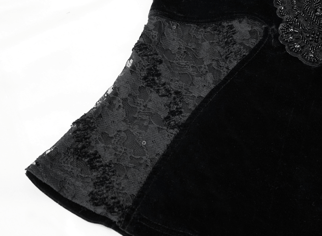 Close-up of gothic women's black velvet top with elegant lace inserts and ruched sleeves.