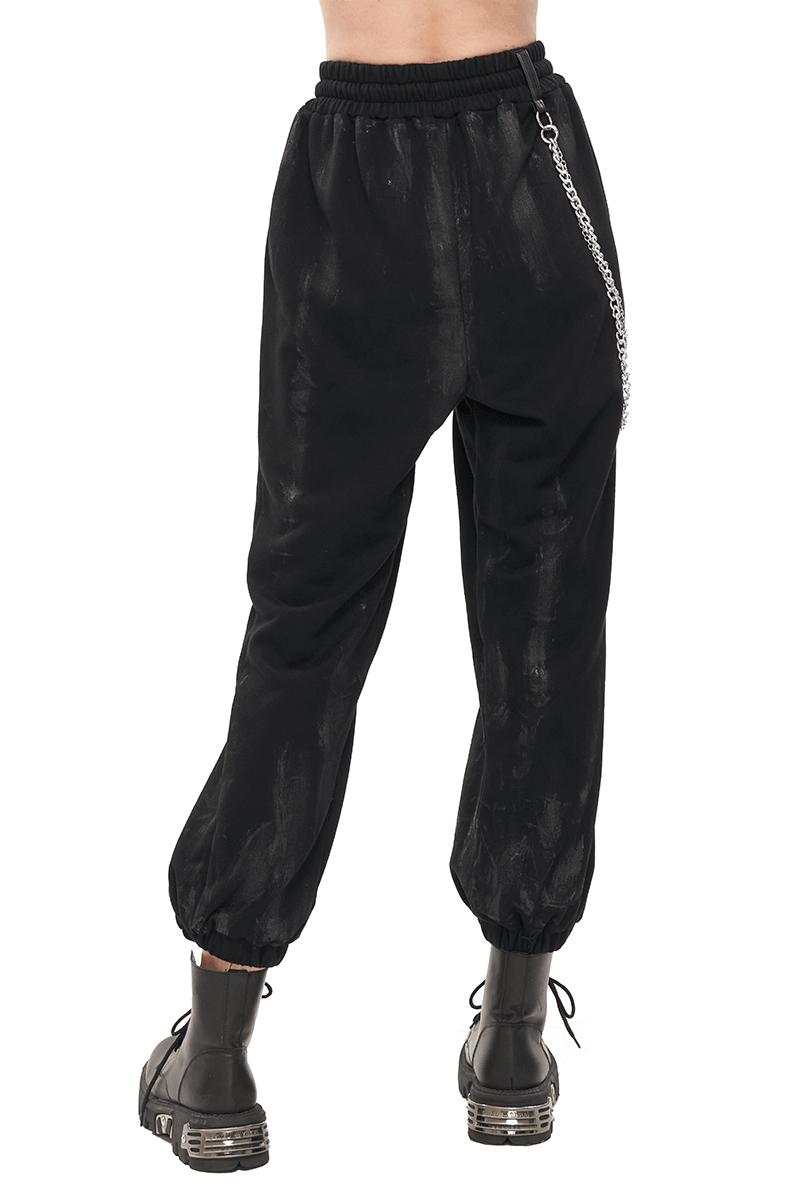 Back view of women's gothic black cargo pants with elastic waist, chain detail, and loose fit, paired with stylish black boots.