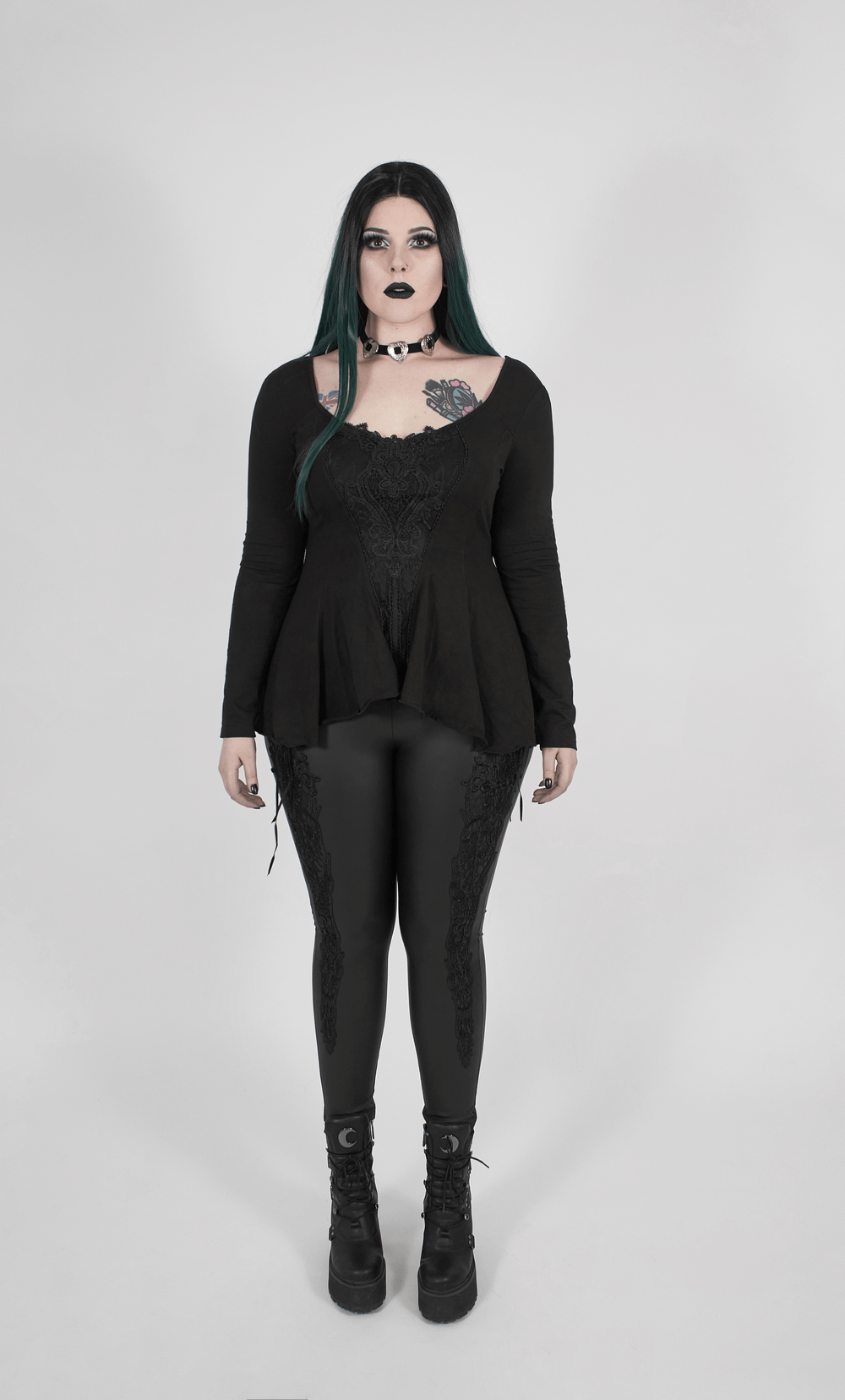 Gothic women's fitted top with lace accent and flared sleeves, paired with stylish black leggings and chunky boots.