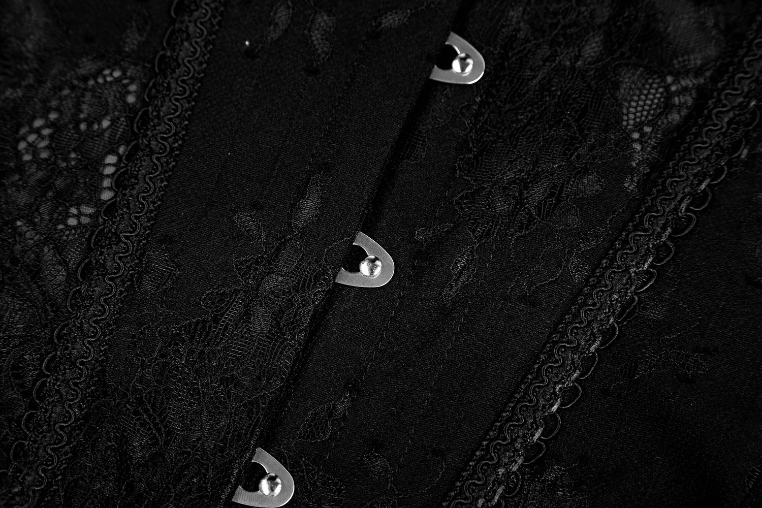 Close-up of a Gothic black lace corset with intricate lace detailing and steel front hooks.