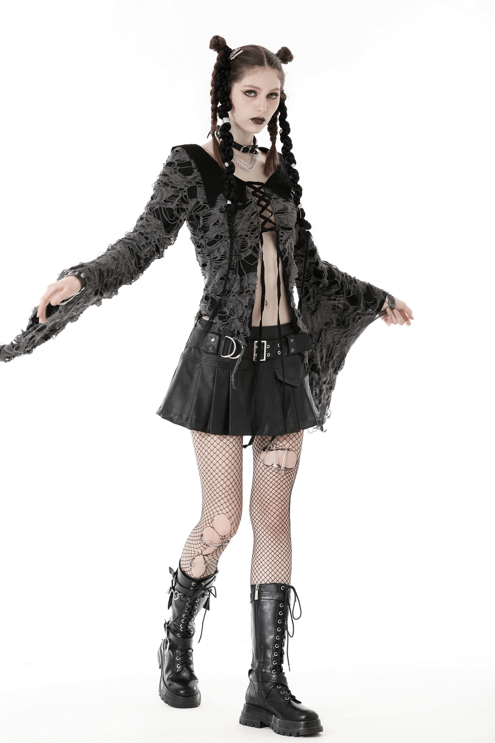Gothic women's lace-up shredded top with dramatic bell sleeves, paired with a short black skirt and fishnet tights.