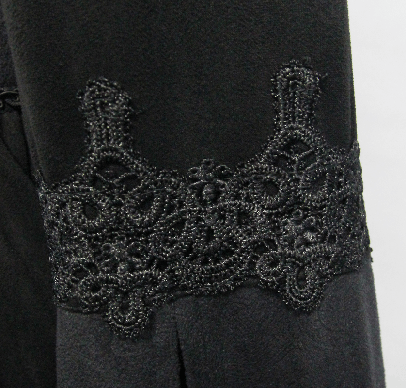 Close-up of intricate black lace detailing on the sleeve of a gothic women's coat.