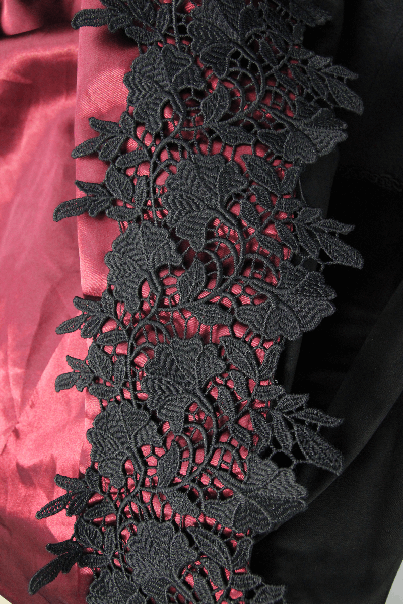 Close-up of elegant black lace trim on a gothic coat, contrasting with rich red satin fabric.