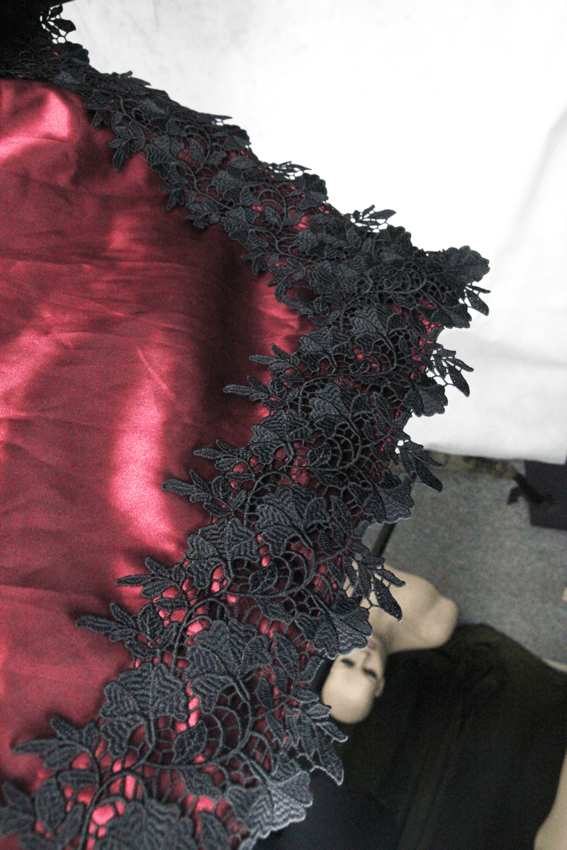 Close-up of black lace trim on elegant red fabric, showcasing gothic style and intricate details.
