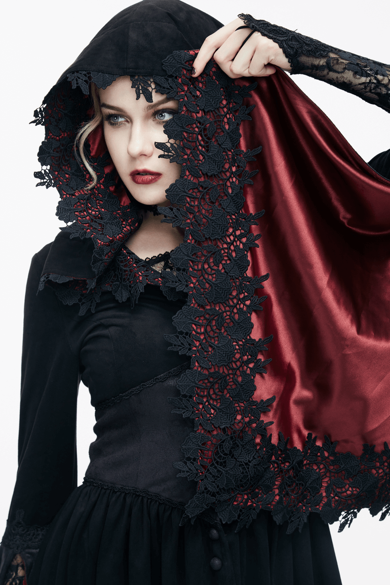 Gothic woman in a black hooded coat, holding a red lace-trimmed shawl, showcasing vintage elegance and style.