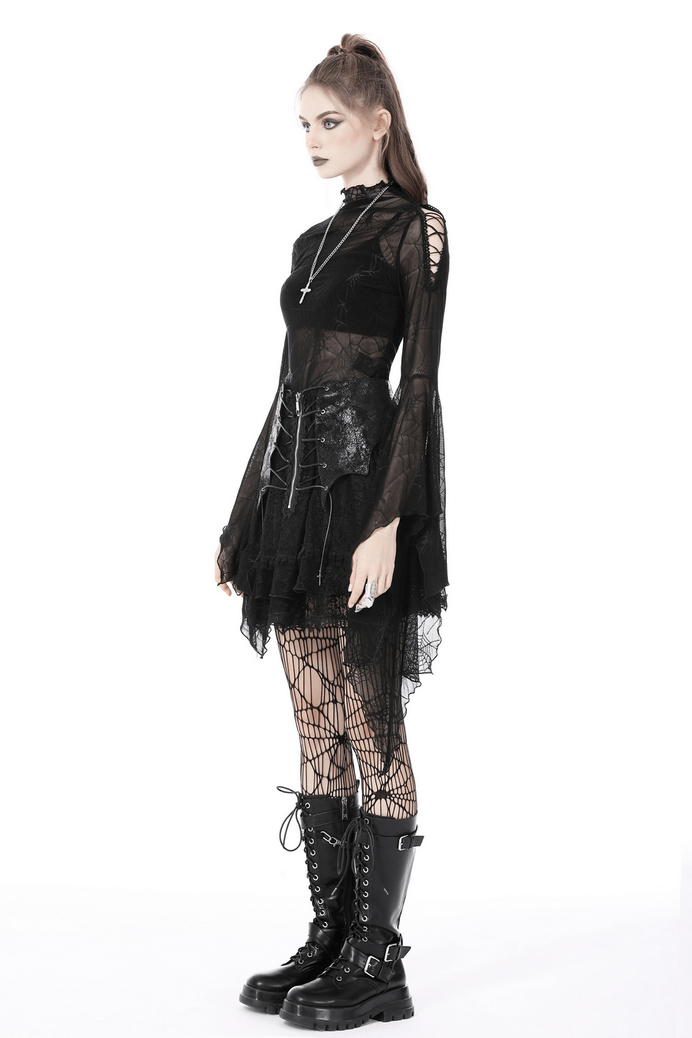 Gothic woman in black mesh spiderweb top with long sleeves, layered over a skirt, paired with fishnet stockings and combat boots.