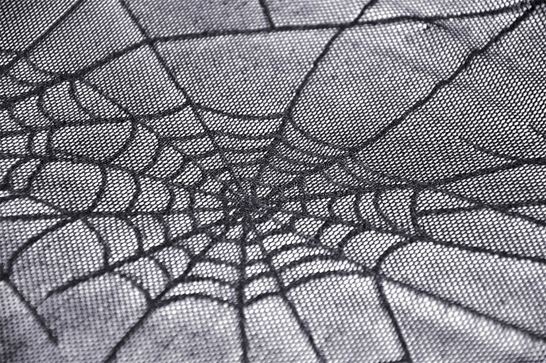 Close-up of intricate black spiderweb design on sheer mesh fabric, perfect for gothic fashion.