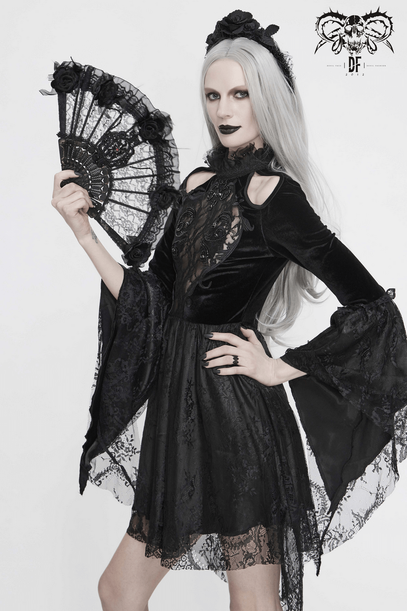 Elegant gothic woman in an off-shoulder black velvet dress with trumpet sleeves, holding a lace fan.
