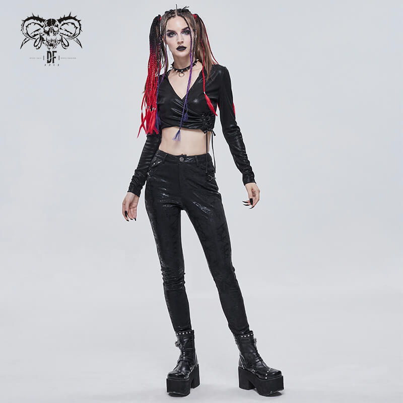 Gothic woman in black slim-fitted pants and crop top with stylish platform boots, showcasing a bold, edgy fashion statement.