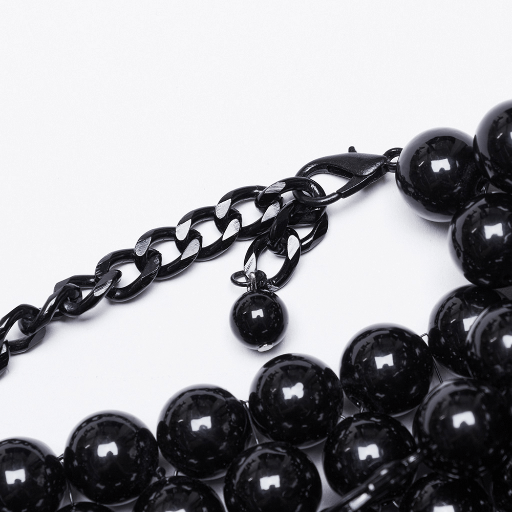 Gothic pearl body accessory close-up with black beads and chain detailing.