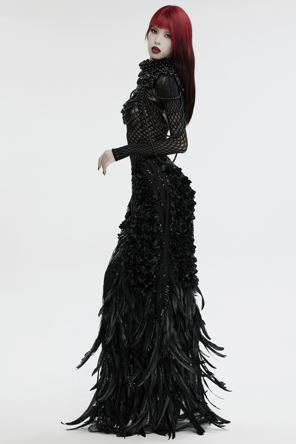 Elegant gothic fashion model wearing a dramatic black dress with floral details and striking red hair.