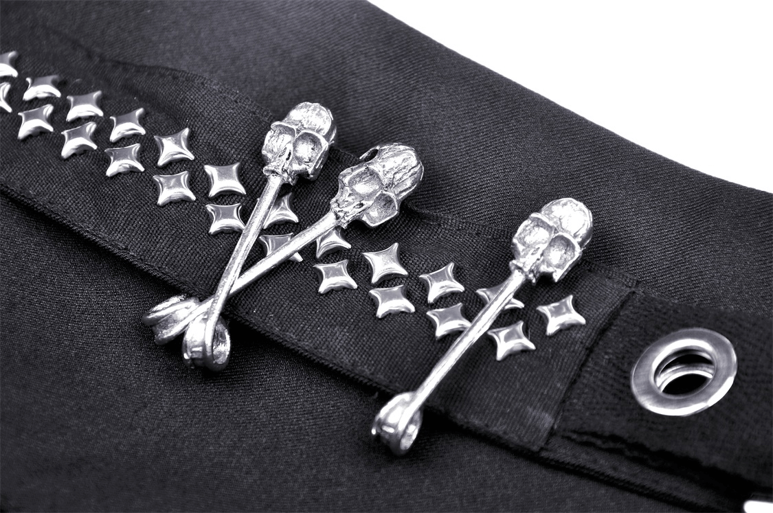 Close-up of edgy skull and star studs on a black gothic mini skirt's waistband, highlighting punk rock style.